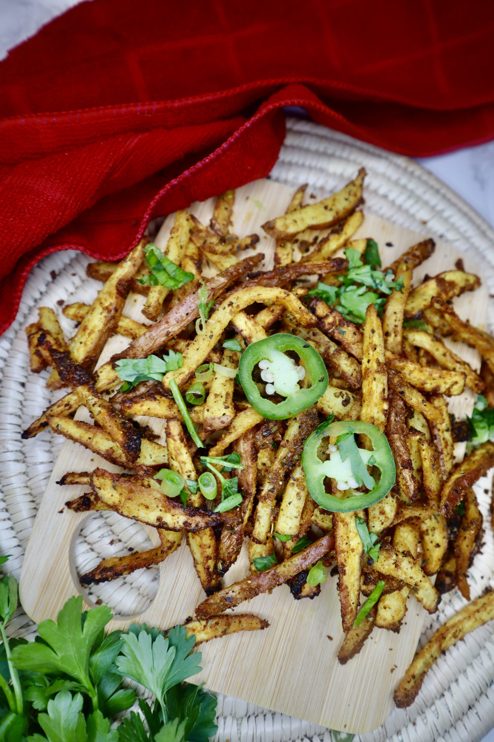 curry paprika fries closeup with jalapeños and red kitchen towel