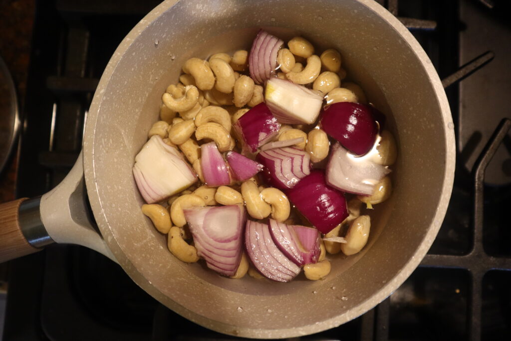 Red onion, cashews, and garlic boiling in a pot of water