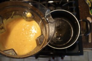 blended carrot apple ginger soup pouring into a pot