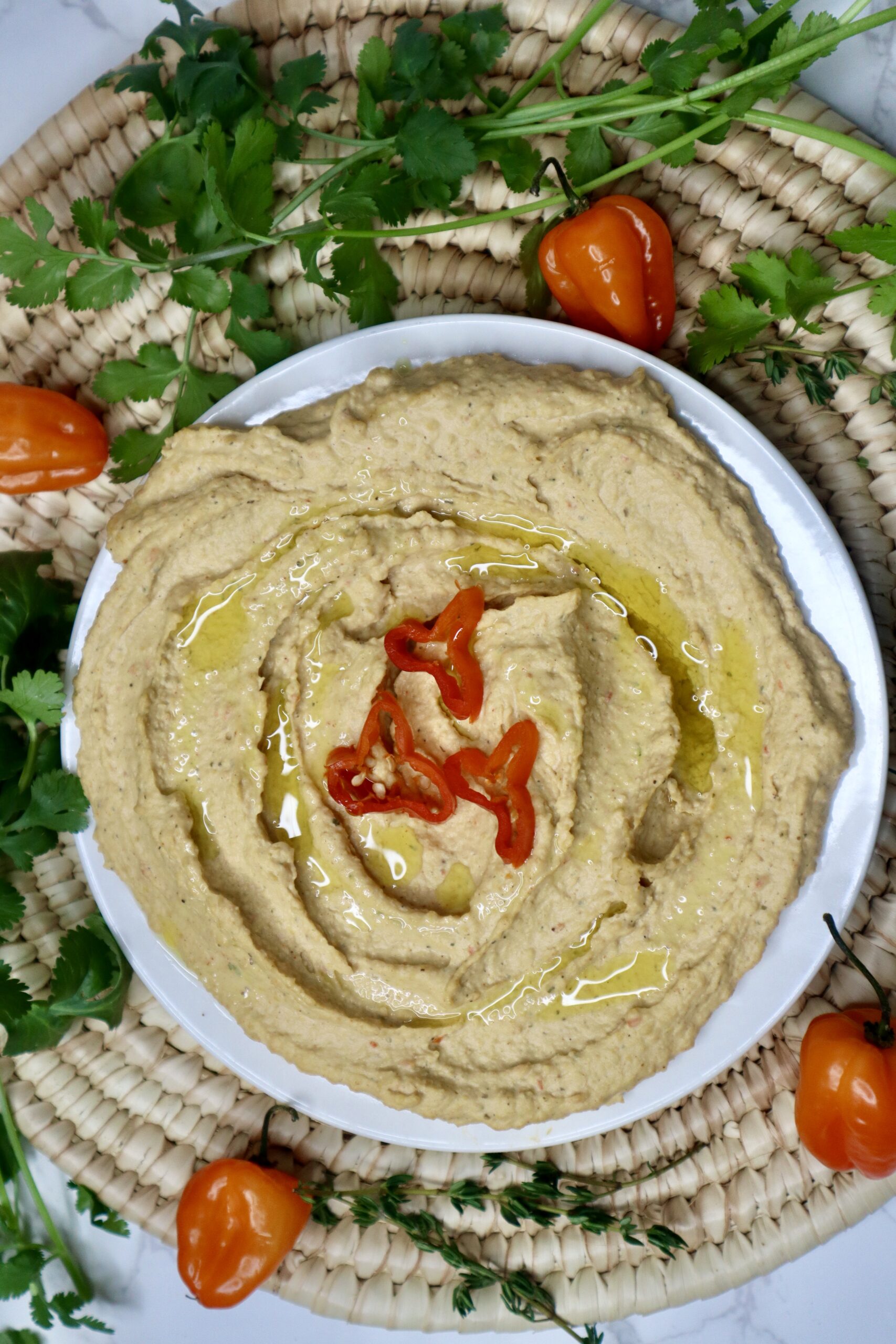 Scotch Bonnet hummus next to peppers and cilantro