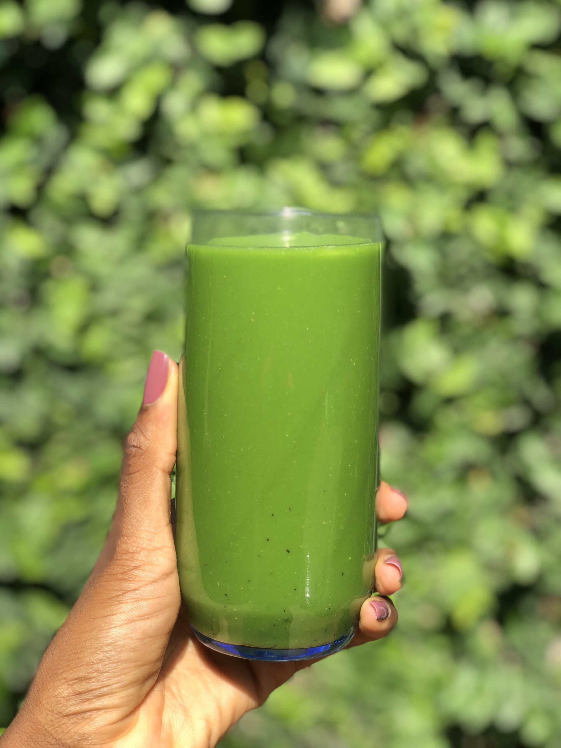 Sweet green juice recipe in front of a bush