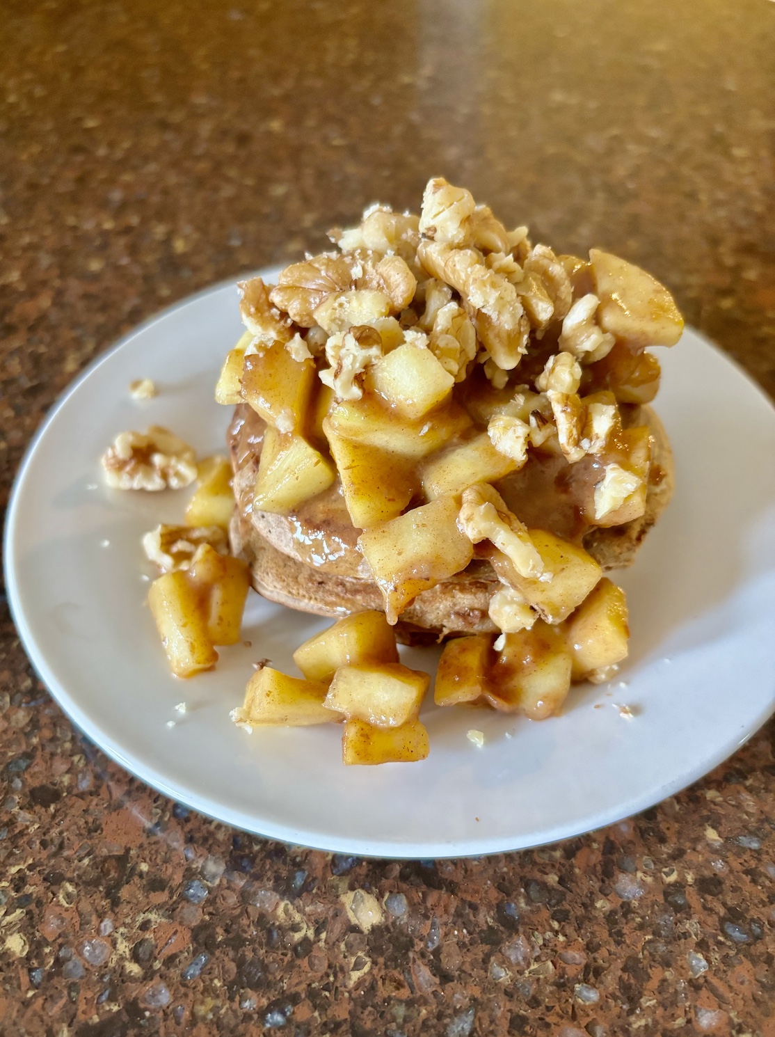 Vegan apple pancakes topped with stewed apples and walnuts