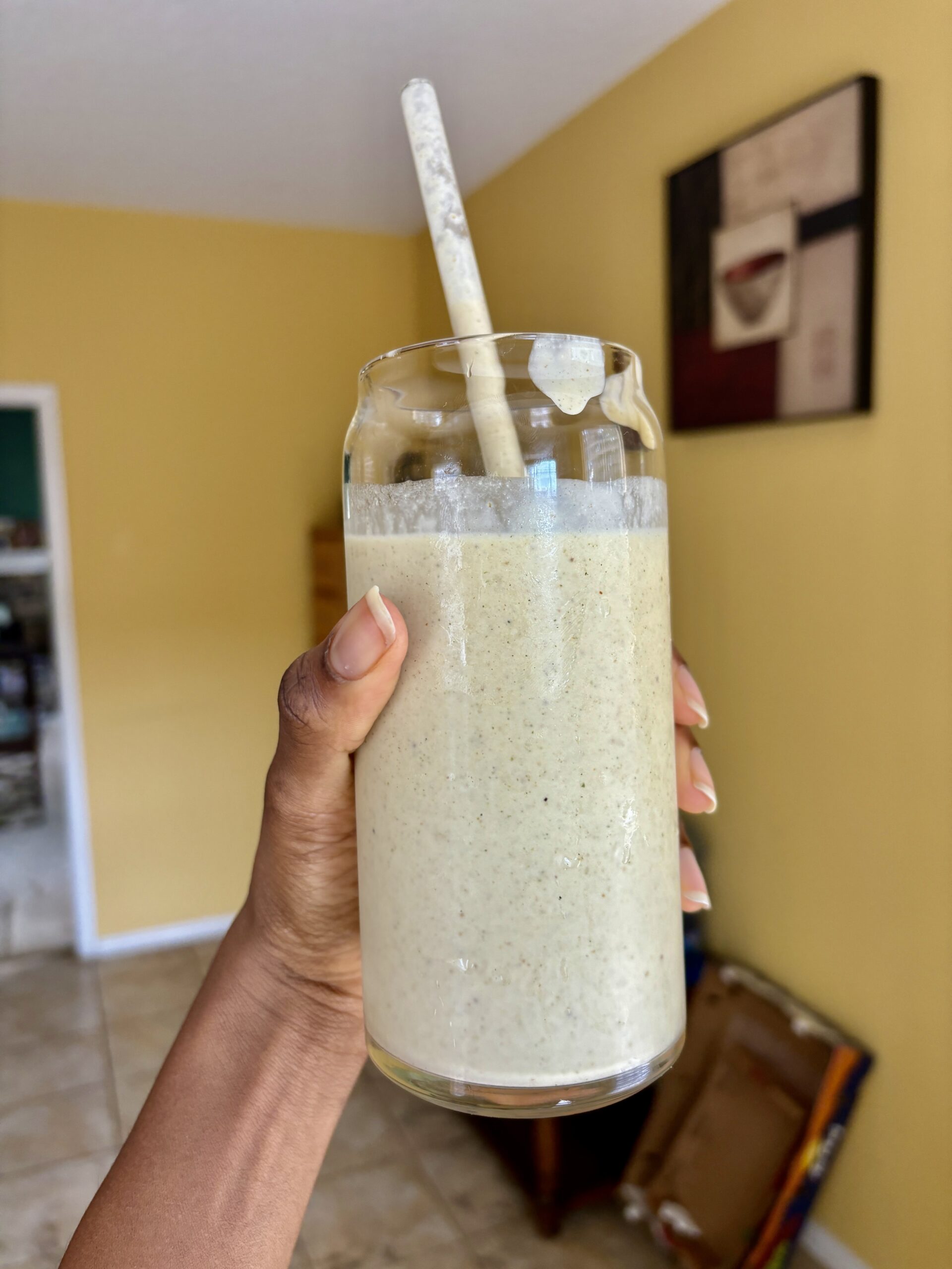 yellow smoothie in clear glass with straw