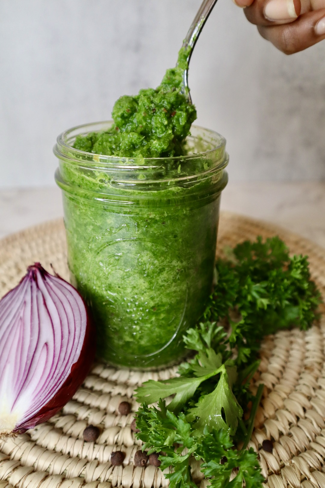 green seasoning in glass jar with spoon serving