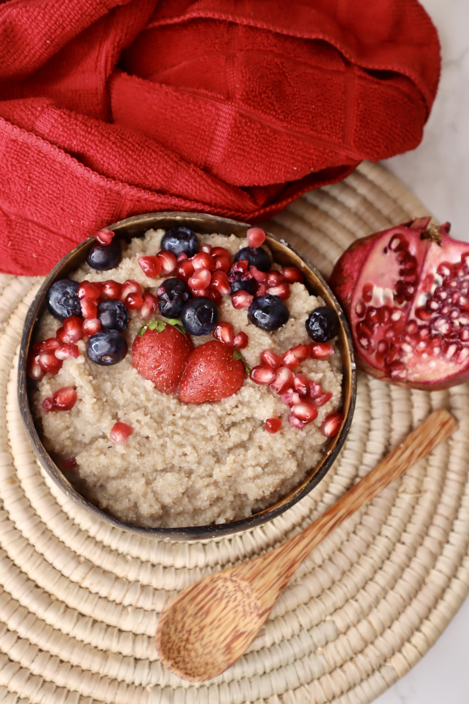 fonio porridge topped with pomegranate. blueberries, and strawberries