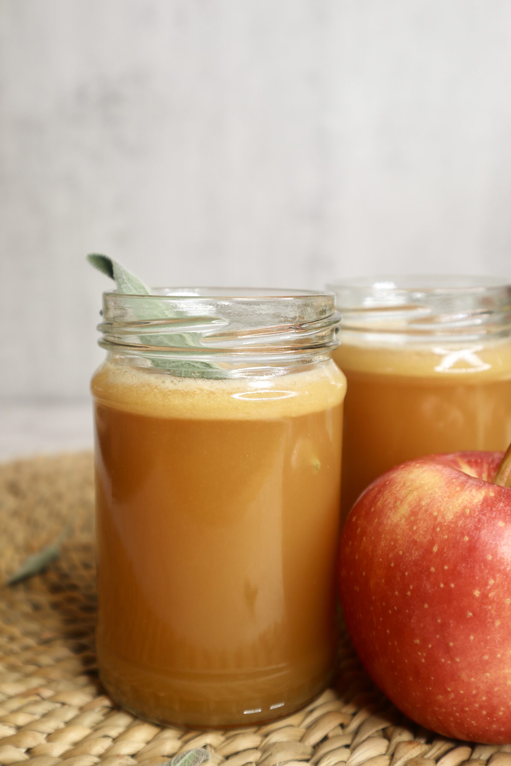 apple juice in a small glass next to an apple