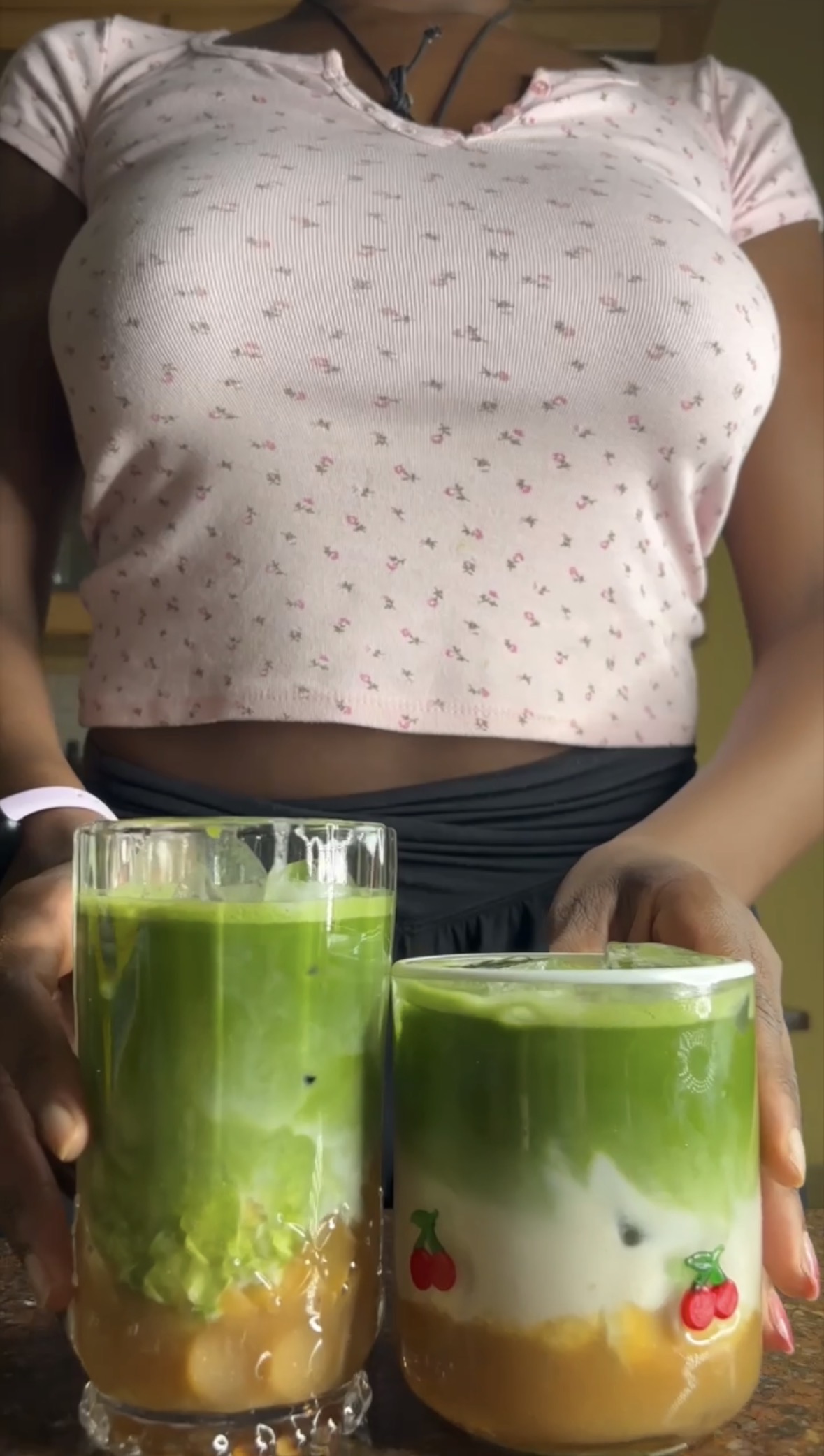 woman holding two matcha lattes with plantain syrup on the bottom